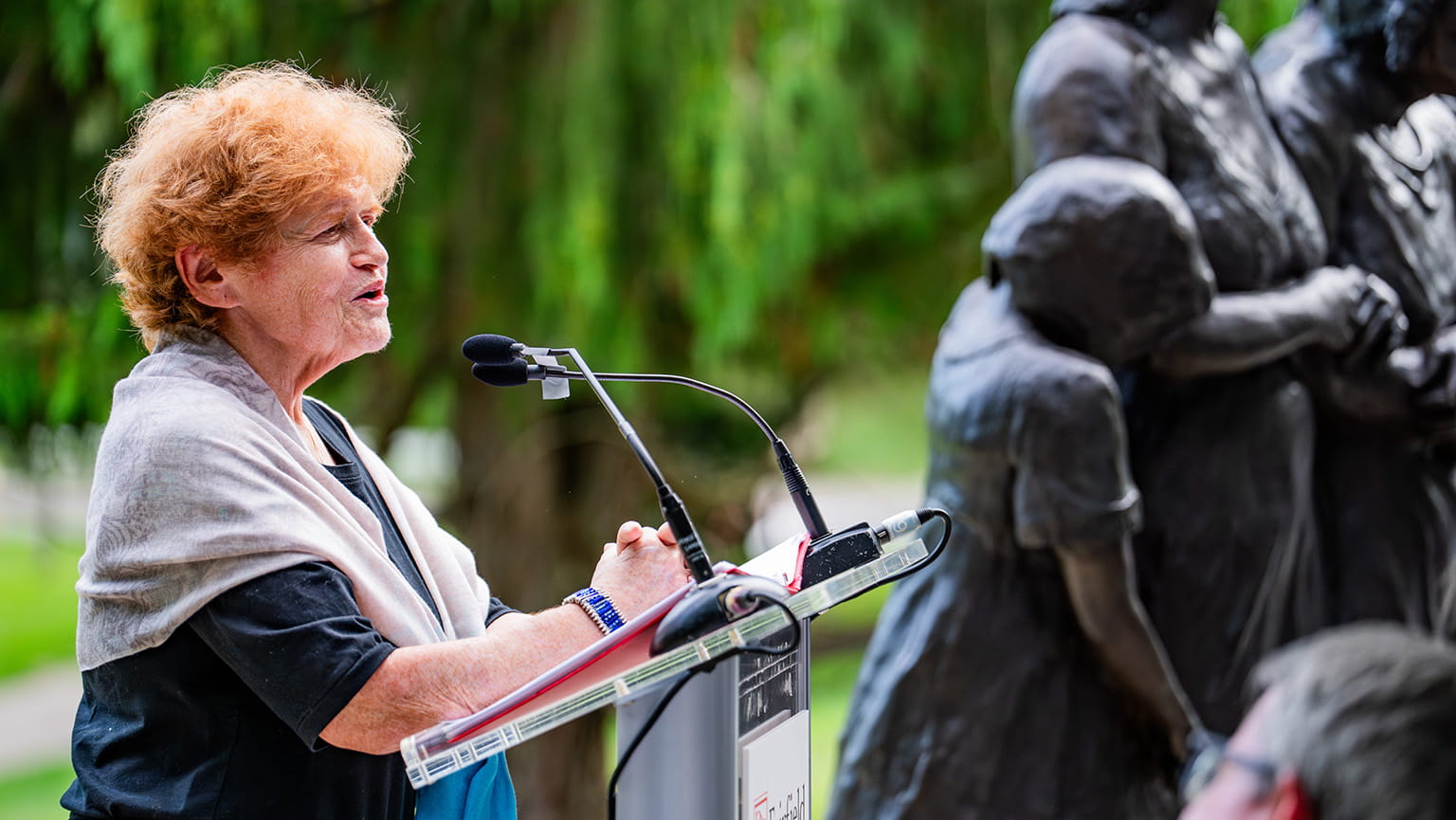 Ambassador Deborah Lipstadt speaking at a podium after the dedication and installation ceremony of the 'She Wouldn’t Take Off Her Boots' memorial sculpture.