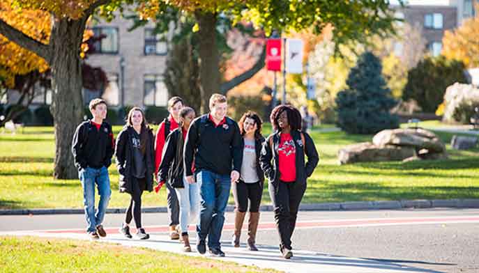 Students walking along a campus sidewalk, engaged in conversation and enjoying their surroundings.