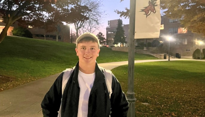 Cian O’Donnell standing in front of pole on the Fairfield University campus, wearing hat.
