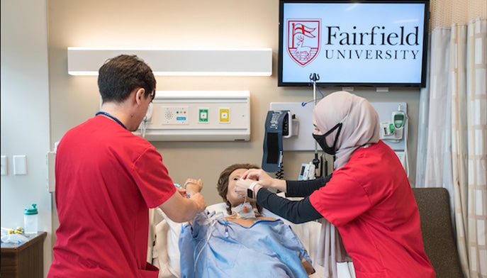 Two students working in hospital like setting, learning how to treat a patient. 