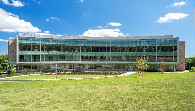 Exterior shot of the brick-and-glass Dolan School of Business building overlooking a lush, green lawn.