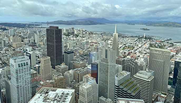 San Francisco skyline viewed from the top of a tower, showcasing iconic buildings against a clear blue sky.