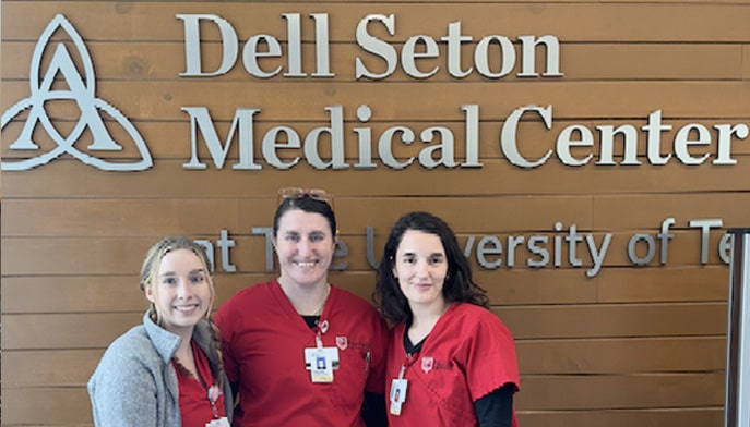 Three students standing in front of the Dell Seton medical center