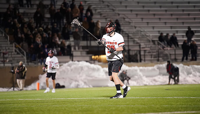 A Fairfield University lacrosse player in action on the field, skillfully holding a stick ready for play.