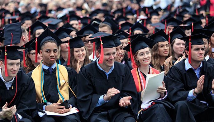 A row of graduates in caps and gowns, seated and ready for their graduation ceremony. 