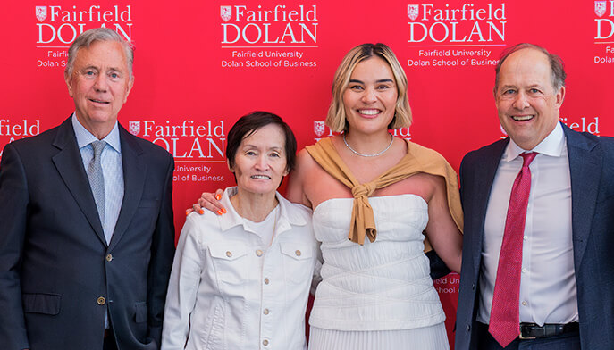 A group of four individuals pose against a bold red wall, enhancing the scene's vibrancy.