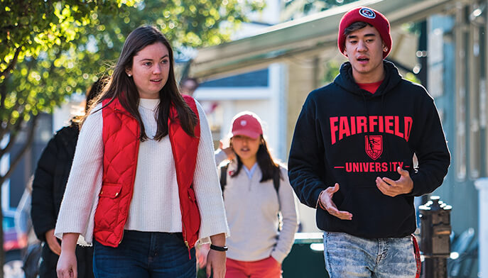 A pair of students strolling down a sidewalk, enjoying their time together.