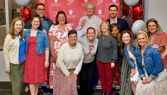 Image of a group of smiling people poses together in front of a colorful banner.