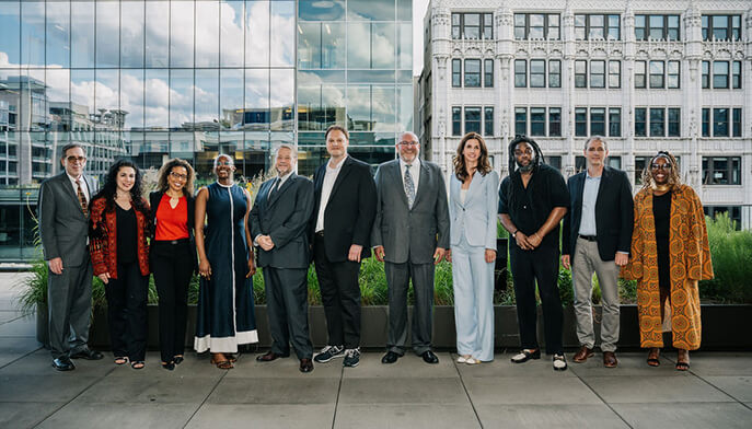 A diverse group of people stands together in front of a building, showcasing camaraderie and community spirit.