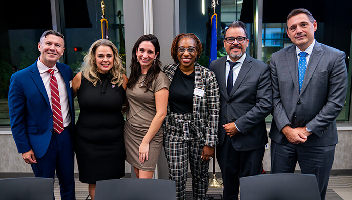 Several individuals dressed in business attire standing together, smiling for a group photo.