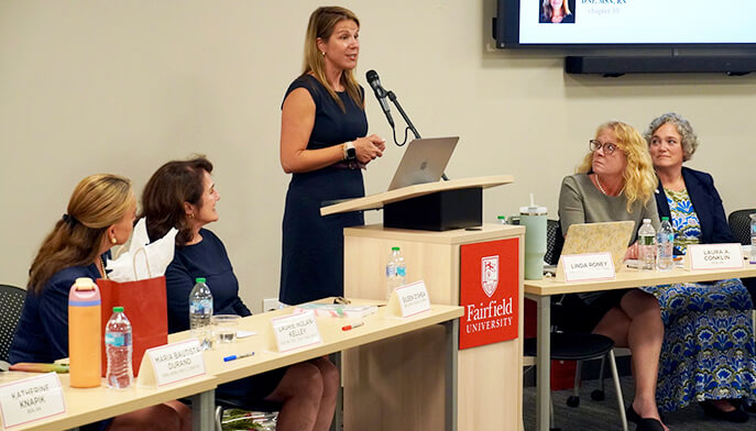A woman presents to an audience, engaging them with her speech and visual aids.