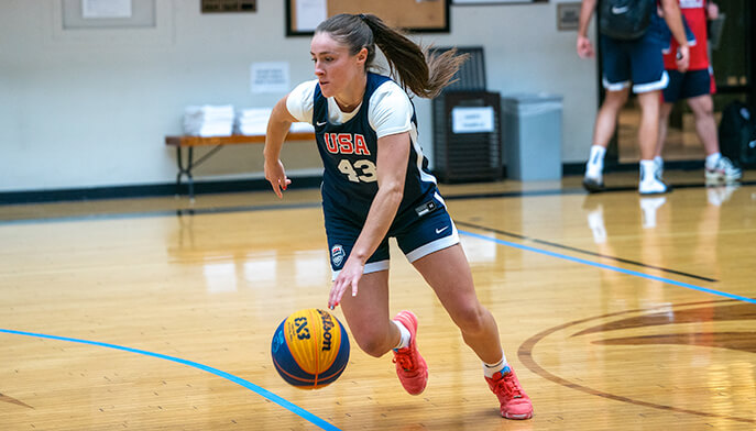 A girl dribbling a basketball on a court, focused and in motion, showcasing her skills and athleticism.