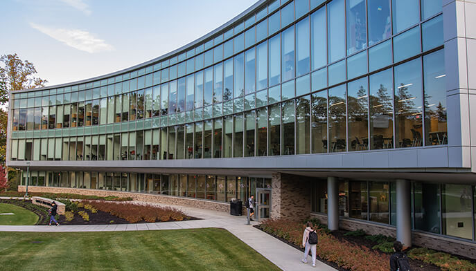 The Dolan School of Business building surrounded by lush green trees and grass, creating a serene and natural environment.