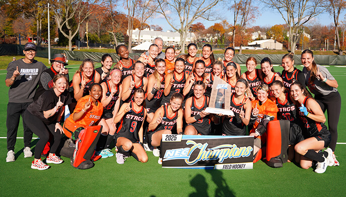 A group photo of the women's field hockey team, showcasing players in uniforms, standing together with smiles.