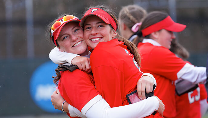 Two female students embracing each other in a warm hug, expressing friendship and support.