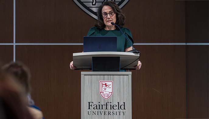 Eileen O’Shea, DNP speaks confidently at a podium, addressing a crowd with enthusiasm.