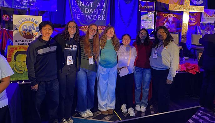 Several individuals pose together in front of a large banner, showcasing a sense of community.