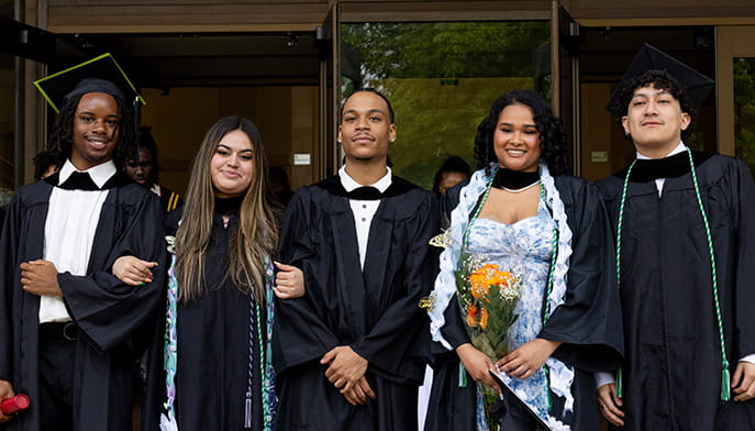 Five Fairfield Bellarmine students standing as a group in caps and gowns following their Commencement ceremony.
