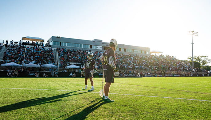 Fairfield Lacrosse players standing on the field with a full crowd before a game on a bright, sunny afternoon.