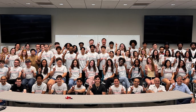 Participants of SEC's Summer Undergraduate Research Residency standing for a group photo in their branded white shirts.