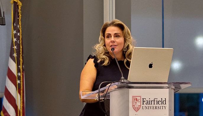 SEHD dean giving a speech while standing at a branded Fairfield University podium.