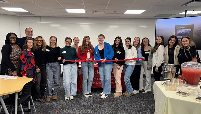 Students and program faculty posing to cut a ribbon for the launch of the Curriculum and Instruction program.
