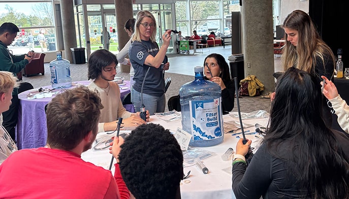 Student members of the Humanitarian Action Club working at a table to assemble water filters.