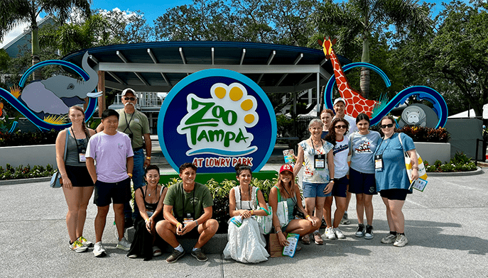 Students from the Vertebrate Zoology Lab posing as a group in front of the Zoo Tampa sign.