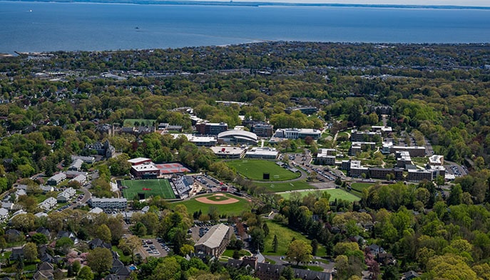 Aerial view of the entirety of Fairfield's sprawling, green campus with the Long Island Sound in the background.