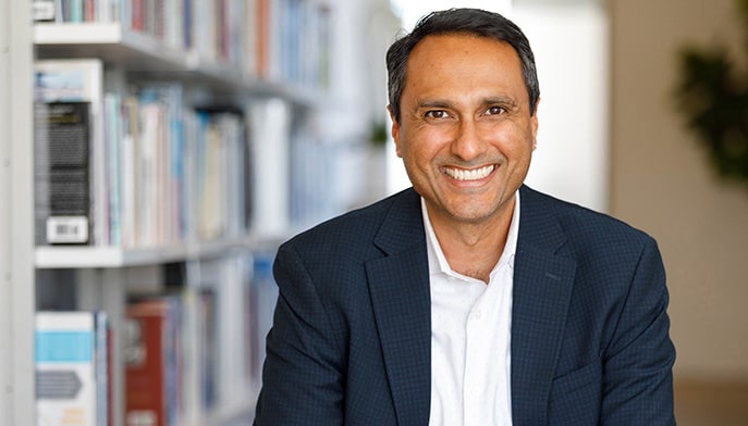 Headshot of Eboo Patel, PhD sitting in an office library setting.