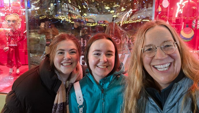 Dr. Linda Henkel with two research students as they stroll NYC during the Christmas holiday season, stopping to take a photo in front of Macy's.