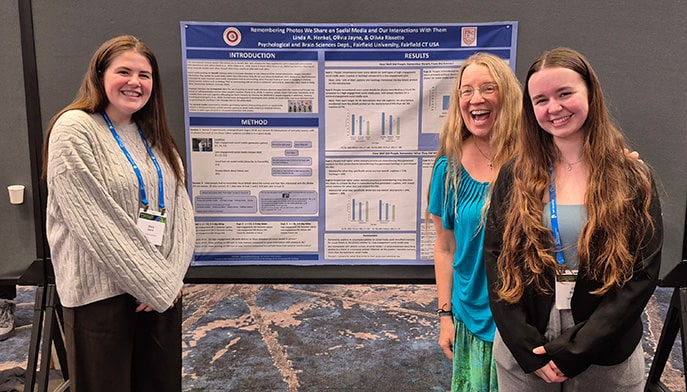Dr. Linda Henkel with two students presenting their research on 'remembering photos we share on social media and our interactions with them'.
