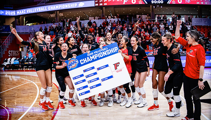 The Fairfield University women's volleyball team proudly holds up a banner, celebrating their achievements and team spirit.