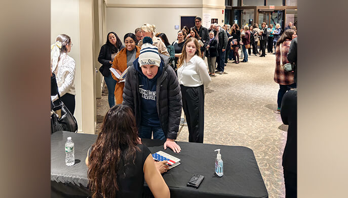 A group of individuals standing in a line, discussing and sharing ideas in a lively atmosphere.