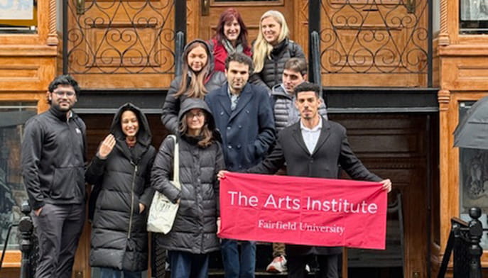 Arts Institute students and staff pose with a banner in front of the Tenement Museum in NYC.