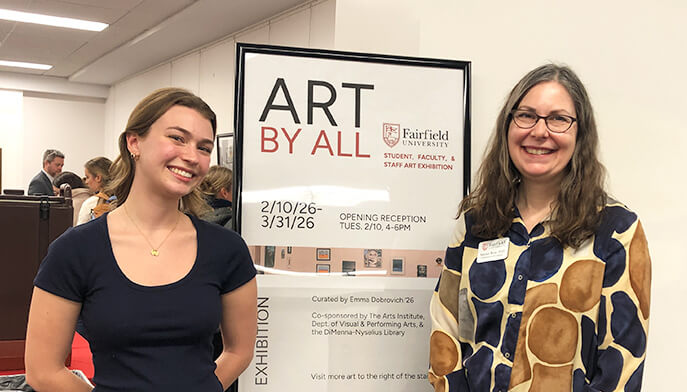 Two smiling women stand beside an 