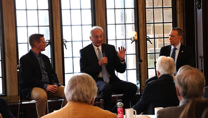 Three colloquium speakers sitting at the front of a brightly-lit windowed room while discussing the importance of liberal arts in an AI-driven economy.