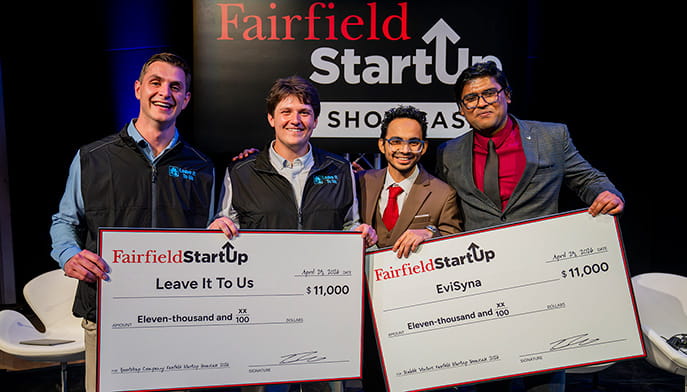 Two teams of two proudly holding their top-prize $11K cash checks after winning the StartUp Showcase in their respective categories.