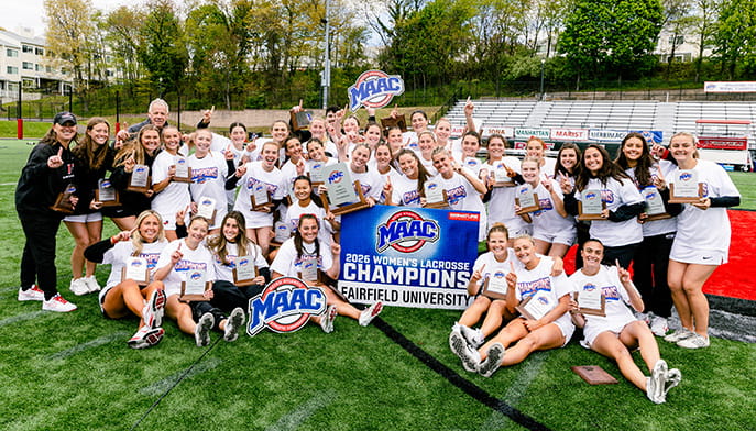 Women's Lacrosse team posing proudly in an all-inclusive group with their various 2026 MAAC Championship signage and awards.