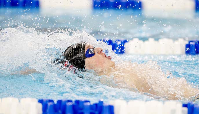 A swimmer glides through the pool with his head down, focused on his stroke.