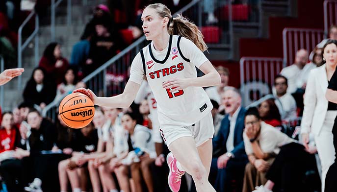 A woman in a white uniform skillfully dribbles a basketball on the court.
