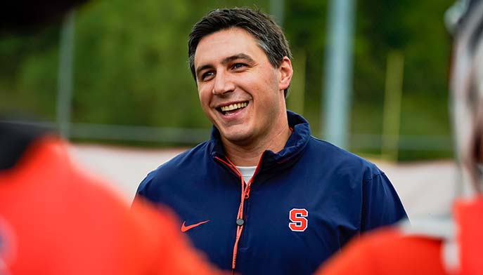  Smiling man wearing an orange and blue jacket, radiating positivity.