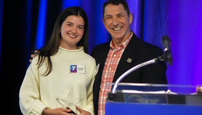 A nursing alumna with the executive director of the camp she's involved with, presenting her with an award.