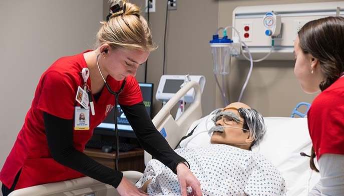 A nurse leans over a patient in a hospital bed, offering assistance and medical care.
