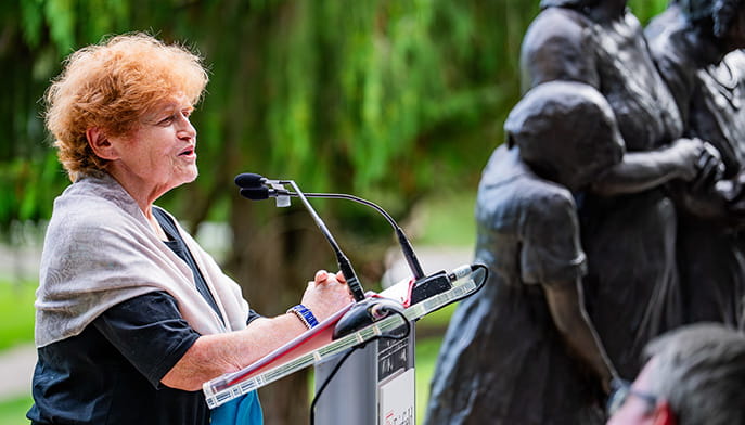 Ambassador Deborah Lipstadt speaking at a podium after the dedication and installation ceremony of the 'She Wouldn’t Take Off Her Boots' memorial sculpture.