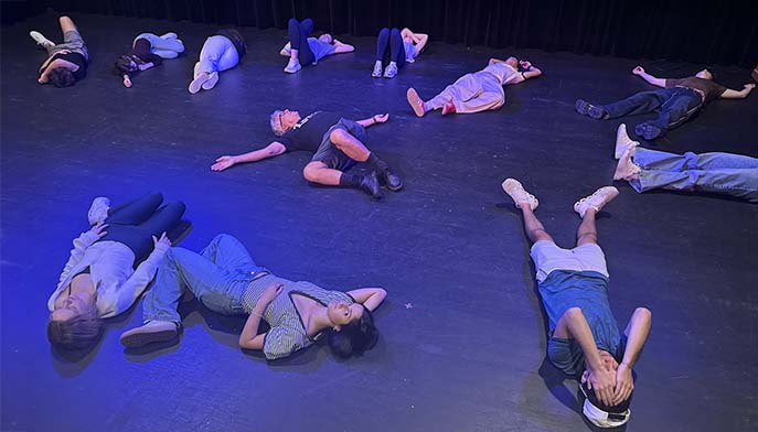 Several people resting on the floor in a dance studio, showcasing a moment of relaxation or teamwork during a session.
