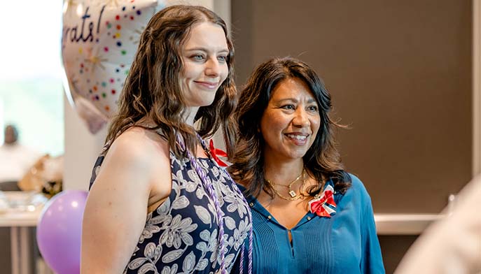 Image of two smiling women posing for the camera beside colorful balloons