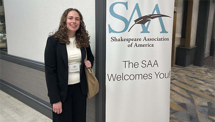 Image of Grace Danielewicz ’27posing next to a conference banner