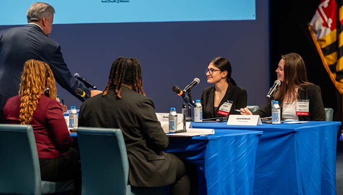 A man addresses a seated group at a table, creating an interactive discussion atmosphere.