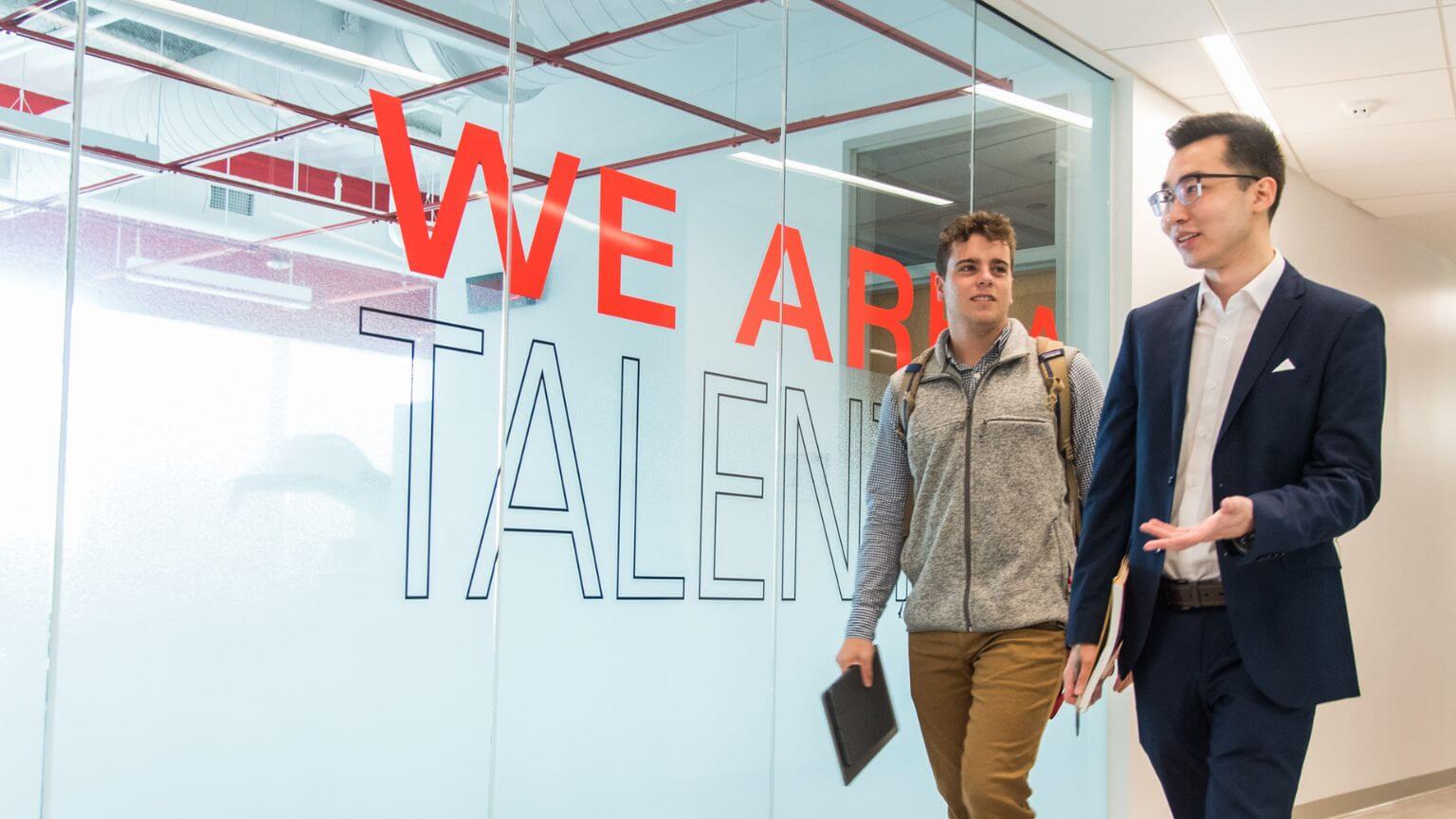 Two students walk down the hallway in the Business School. 